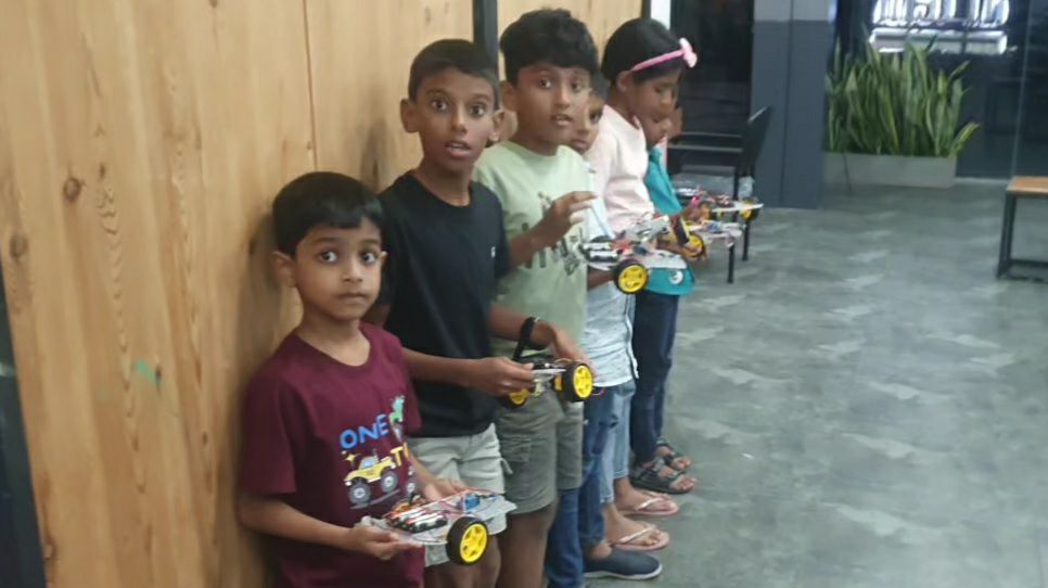 Young learners holding the robot cars they built